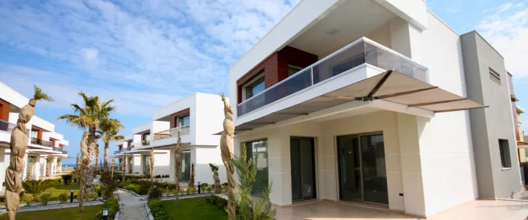 Modern luxury villas with landscaped pathways and palm trees in a residential community environment.