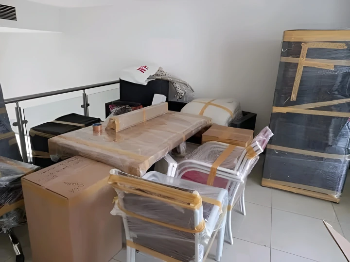 Furniture movers in Dubai preparing securely wrapped household furniture including dining tables chairs wardrobes and mattresses