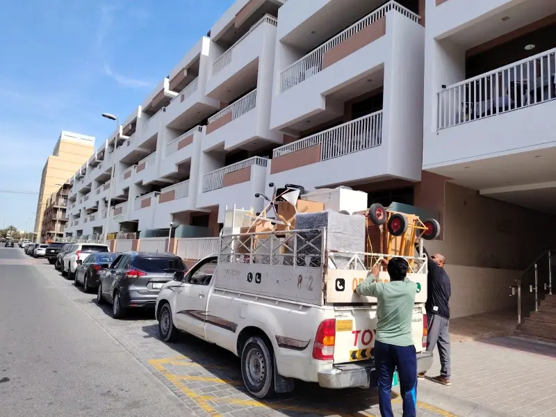 Movers in Dubai Marina loading a moving truck outside a residential apartment building.