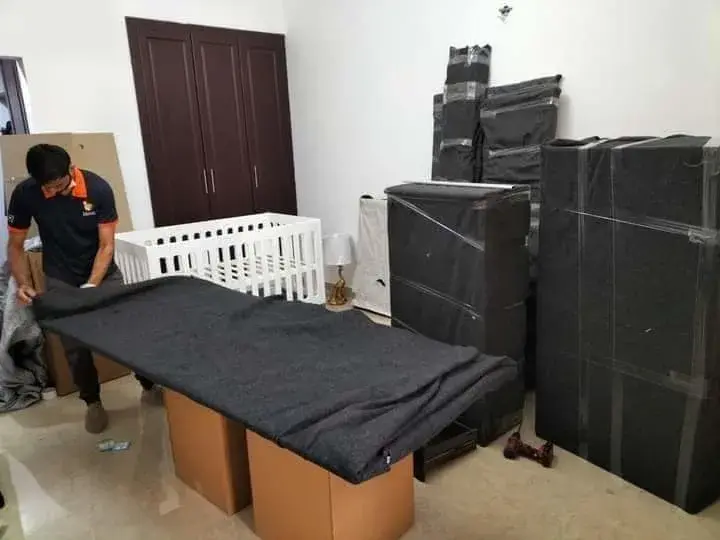 Movers and Packers in Dubai Silicon Oasis wrapping valuable household furniture with protective moving blankets