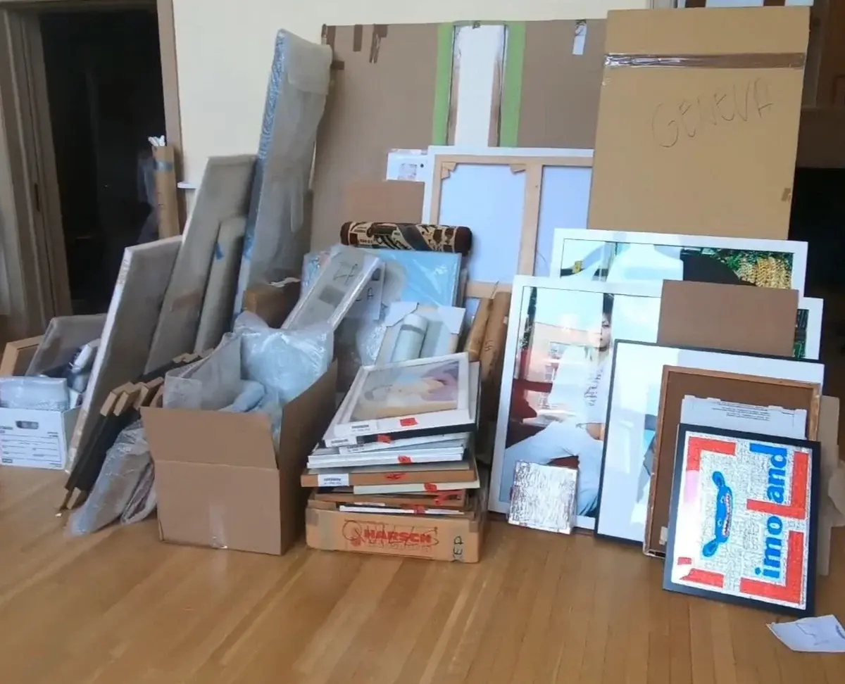 Fine art movers preparing paintings and framed artwork with professional packing materials before secure transportation.