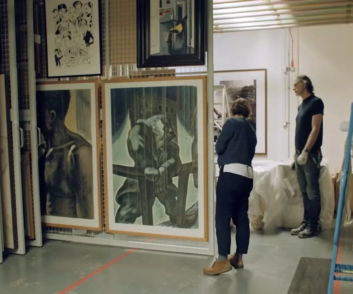 Professionals handling framed artwork inside a secure gallery storage area before transportation.